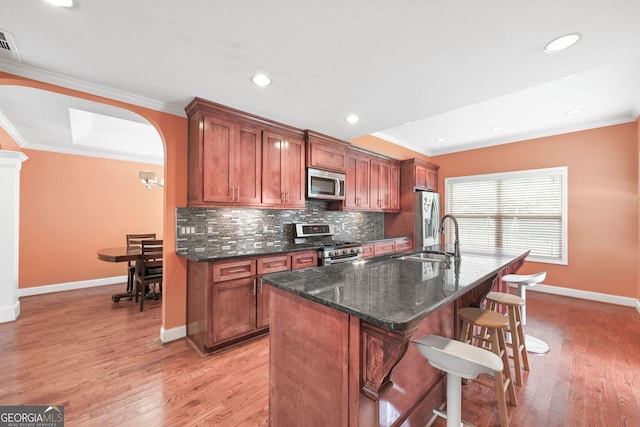 2670 Trotters Pointe Dr, Snellville, GA 30039 - kitchen featuring stainless steel appliances, crown molding, a kitchen bar, decorative backsplash, and a center island with sink
