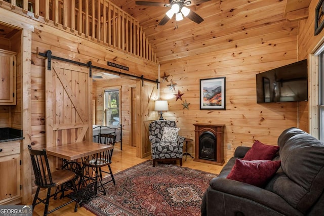 72 Bentley Cv, Murphy, NC 28960 - living room featuring a barn door, light wood-style flooring, wood walls, wooden ceiling, and a ceiling fan