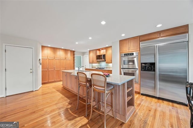 1416 Vernon Rdg, Close, Dunwoody, GA 30338 - kitchen featuring appliances with stainless steel finishes, light wood-style flooring, recessed lighting, open shelves, and a kitchen island with sink
