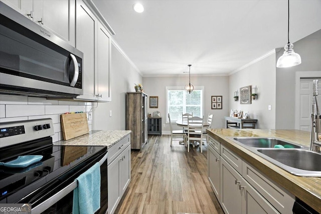 161 Fairway Cir, Macon, GA 31211 - kitchen featuring stainless steel appliances, crown molding, light wood-type flooring, light countertops, and hanging light fixtures
