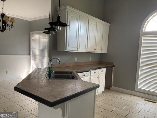 550 Masters Cir, Dublin, GA 31021 - kitchen featuring a peninsula, a chandelier, light tile patterned flooring, white cabinetry, and a kitchen breakfast bar