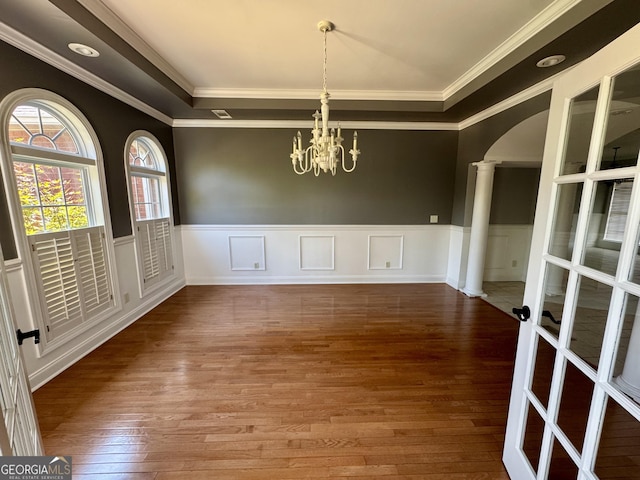 550 Masters Cir, Dublin, GA 31021 - unfurnished dining area featuring wood-type flooring, arched walkways, ornamental molding, a chandelier, and wainscoting
