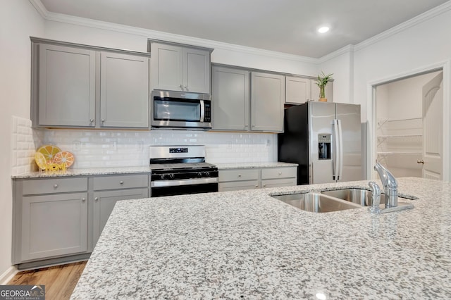 7730 Demeter Dr, Fairburn, GA 30213 - kitchen with appliances with stainless steel finishes, gray cabinetry, crown molding, light stone counters, and backsplash
