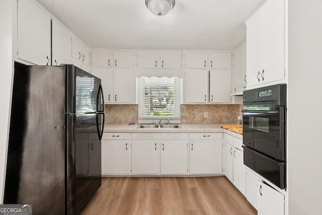 6770 Burkhead Dr, Union City, GA 30291 - kitchen with black appliances, a warming drawer, light wood-type flooring, white cabinets, and tile counters