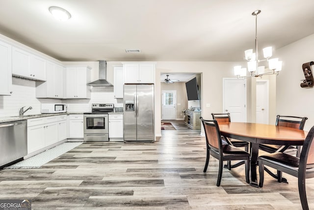 230 Thorpe Rd, Jackson, GA 30233 - kitchen featuring appliances with stainless steel finishes, wall chimney range hood, light wood-type flooring, a chandelier, and tasteful backsplash