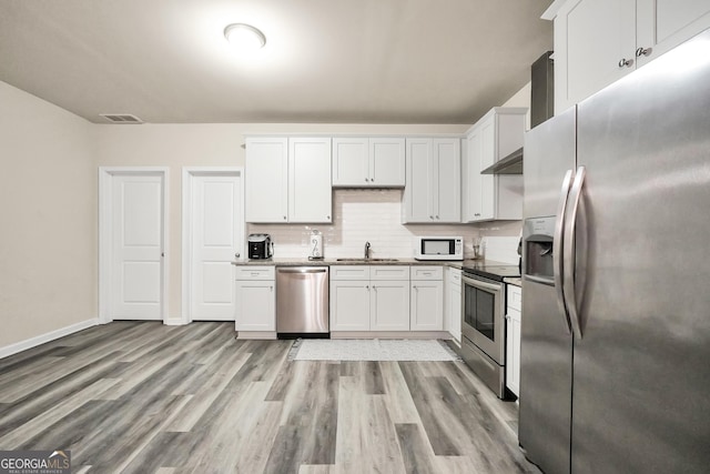 230 Thorpe Rd, Jackson, GA 30233 - kitchen featuring appliances with stainless steel finishes, white cabinetry, tasteful backsplash, and light wood-style flooring