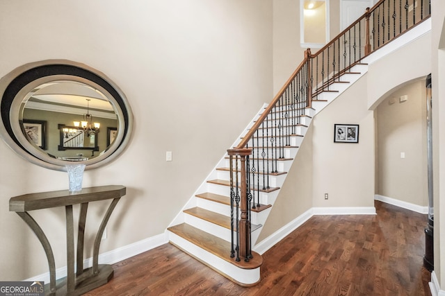 204 Carmell Ct, Mcdonough, GA 30252 - stairway featuring arched walkways, wood finished floors, a high ceiling, and a chandelier