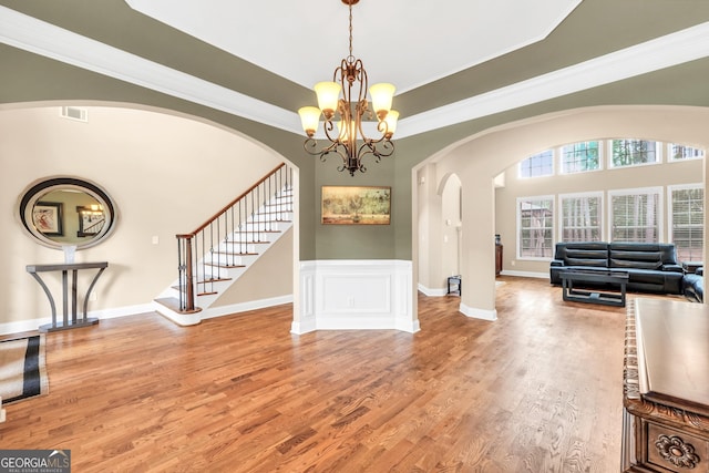 204 Carmell Ct, Mcdonough, GA 30252 - entrance foyer with arched walkways, light wood finished floors, a chandelier, stairs, and a wainscoted wall