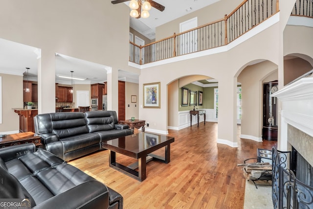 204 Carmell Ct, Mcdonough, GA 30252 - living area with ceiling fan, light wood-style floors, a fireplace with flush hearth, a towering ceiling, and arched walkways