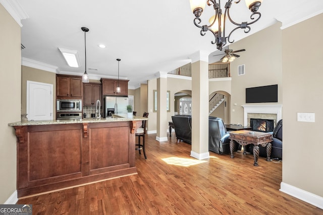 204 Carmell Ct, Mcdonough, GA 30252 - kitchen with appliances with stainless steel finishes, a lit fireplace, a ceiling fan, crown molding, and arched walkways