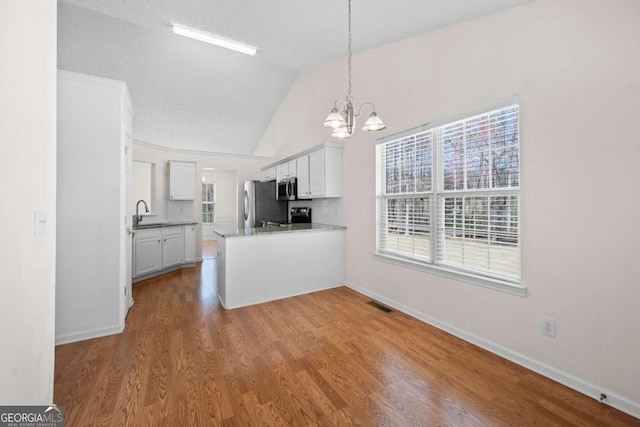 3076 Harris Mill Ct, Duluth, GA 30096 - kitchen featuring a chandelier, appliances with stainless steel finishes, vaulted ceiling, a peninsula, and wood finished floors