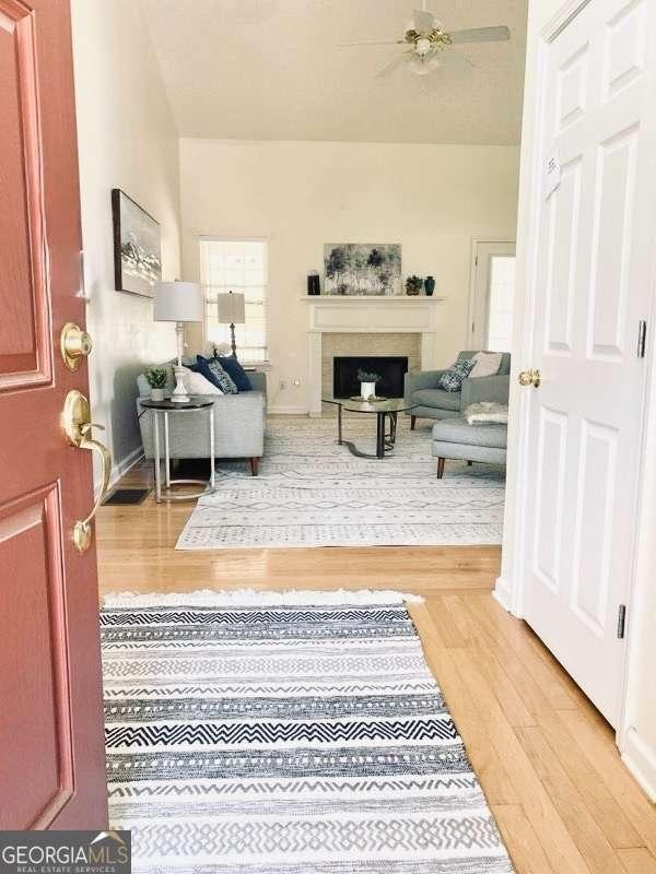 3076 Harris Mill Ct, Duluth, GA 30096 - living room featuring light wood-type flooring, a fireplace, and ceiling fan