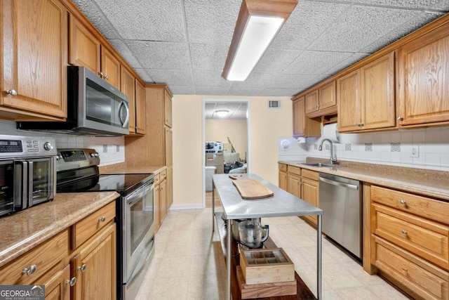 3076 Harris Mill Ct, Duluth, GA 30096 - kitchen with stainless steel appliances, backsplash, light countertops, and brown cabinetry