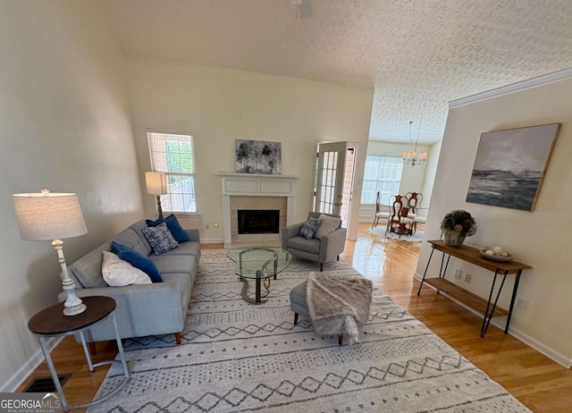 3076 Harris Mill Ct, Duluth, GA 30096 - living room featuring plenty of natural light, a textured ceiling, a chandelier, wood finished floors, and a fireplace