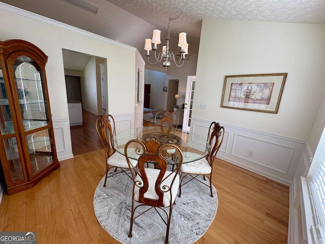 3076 Harris Mill Ct, Duluth, GA 30096 - dining area with a chandelier, light wood-type flooring, a textured ceiling, wainscoting, and a decorative wall