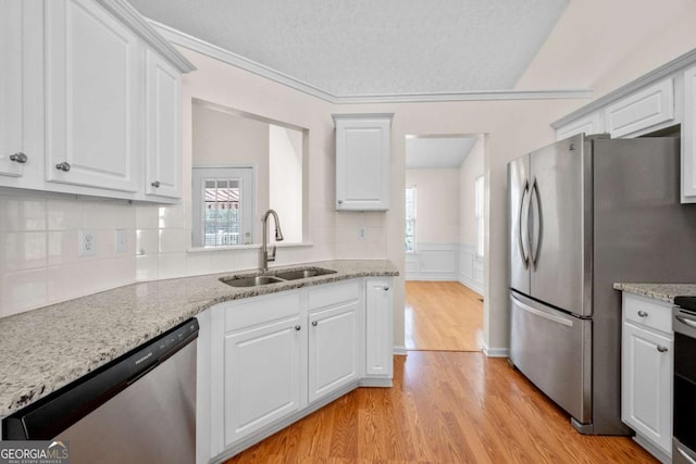 3076 Harris Mill Ct, Duluth, GA 30096 - kitchen with appliances with stainless steel finishes, light wood-style flooring, plenty of natural light, white cabinets, and a wainscoted wall