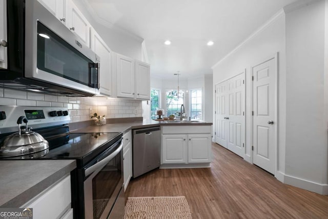 3047 Standing Rock Ct, Lithia Springs, GA 30122 - kitchen with appliances with stainless steel finishes, crown molding, light wood finished floors, white cabinets, and tasteful backsplash