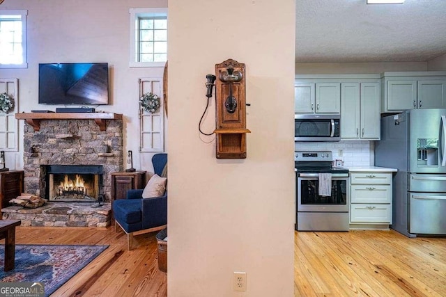 104 Buck Run E, Dahlonega, GA 30533 - kitchen with appliances with stainless steel finishes, light wood finished floors, tasteful backsplash, a stone fireplace, and open floor plan