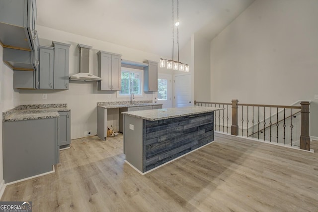 48 Bluejay Ct, Monticello, GA 31064 - kitchen with wall chimney exhaust hood, gray cabinetry, light wood finished floors, a kitchen island, and high vaulted ceiling