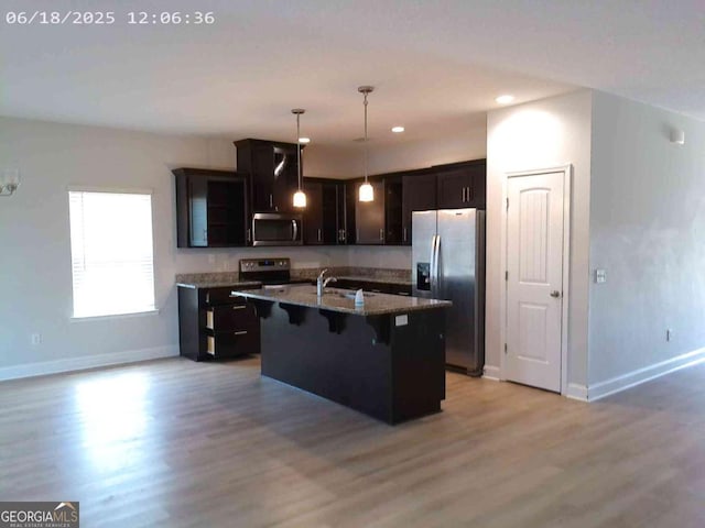 299 Mcclelland Loop NE, Ludowici, GA 31316 - kitchen featuring appliances with stainless steel finishes, a kitchen bar, light wood-style floors, stone counters, and a kitchen island with sink