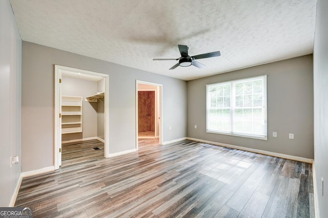 30 Red Bird Ln, Ellijay, GA 30540 - unfurnished bedroom featuring wood finished floors, a spacious closet, a closet, a ceiling fan, and a textured ceiling