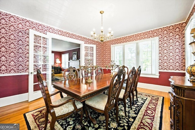 3579 Overlook Ave, Macon, GA 31204 - dining space with wallpapered walls, a chandelier, ornamental molding, wood finished floors, and wainscoting