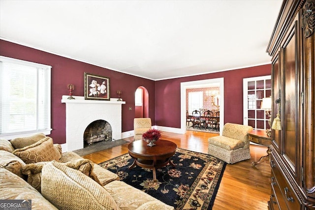 3579 Overlook Ave, Macon, GA 31204 - living room with arched walkways, wood finished floors, a brick fireplace, and crown molding