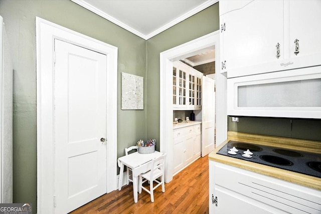 3579 Overlook Ave, Macon, GA 31204 - kitchen with crown molding, black electric cooktop, wood finished floors, white cabinets, and light countertops