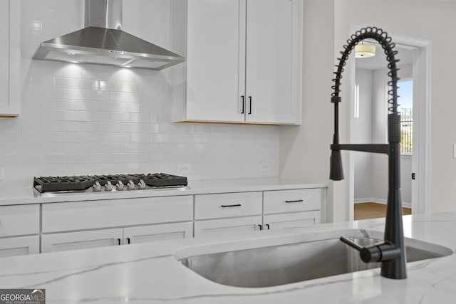 1692 Juniper Berry Way, Loganville, GA 30052 - kitchen featuring wall chimney exhaust hood, stainless steel gas stovetop, backsplash, white cabinets, and light stone counters