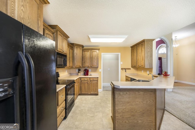 112 Huntwood Ln, Kathleen, GA 31047 - kitchen featuring black appliances, a peninsula, light countertops, brown cabinetry, and a textured ceiling