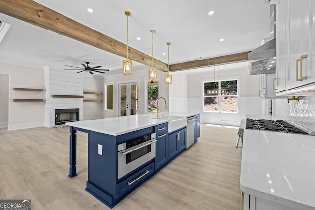 1131 Glen Eagle Dr, Greensboro, GA 30642 - kitchen with blue cabinetry, stainless steel appliances, a ceiling fan, light wood finished floors, and a breakfast bar area