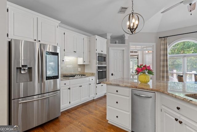 660 Milton Dr, Mcdonough, GA 30252 - kitchen with stainless steel appliances, backsplash, a chandelier, white cabinetry, and light stone counters