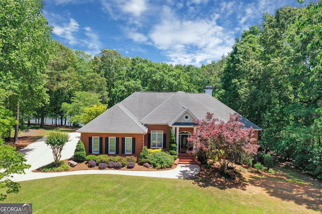660 Milton Dr, Mcdonough, GA 30252 - greek revival house featuring a front yard, a chimney, brick siding, and a forest view