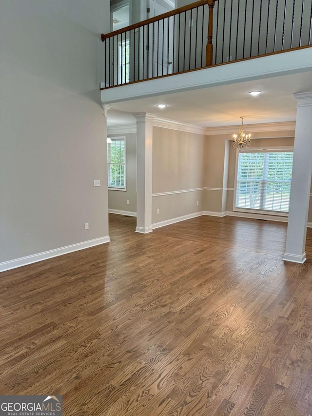 205 Huntington Shoals Dr, Athens, GA 30606 - unfurnished living room with crown molding, a chandelier, a towering ceiling, dark wood-style floors, and decorative columns