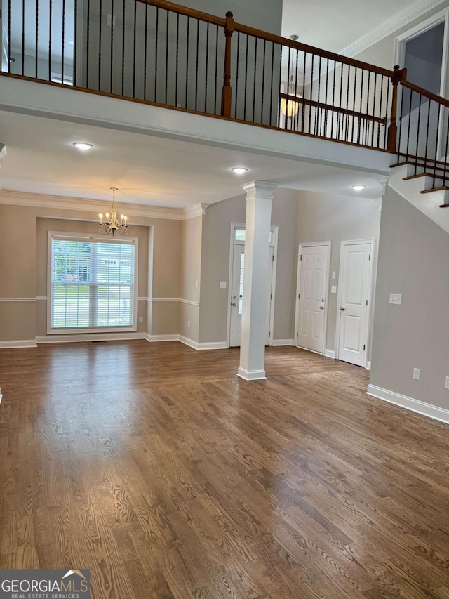 205 Huntington Shoals Dr, Athens, GA 30606 - unfurnished living room with ornamental molding, a chandelier, wood finished floors, a towering ceiling, and stairway
