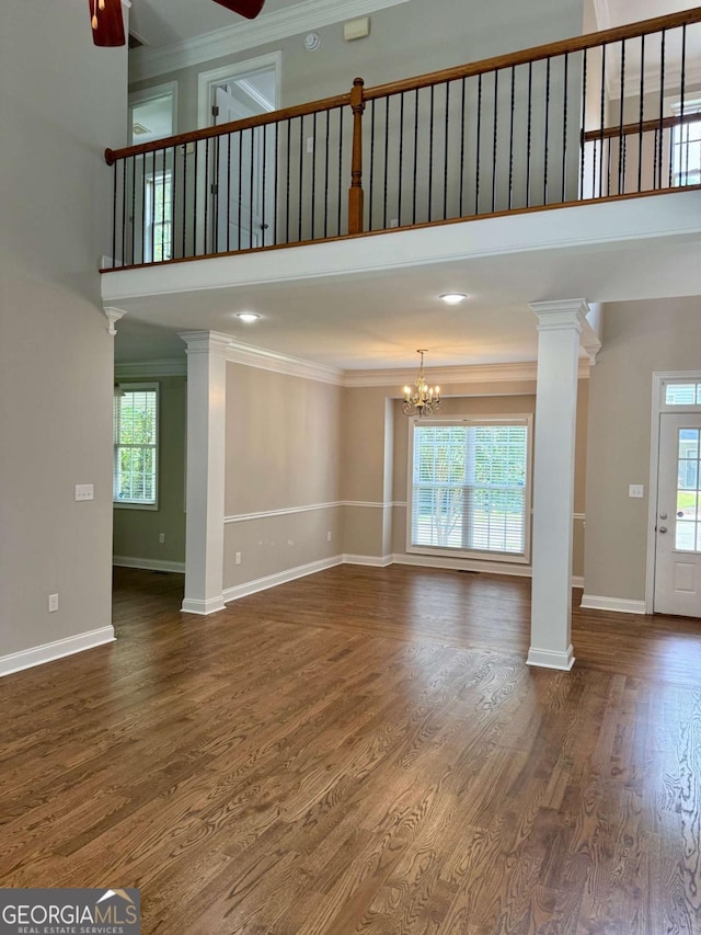 205 Huntington Shoals Dr, Athens, GA 30606 - unfurnished living room featuring a high ceiling, ornamental molding, ornate columns, a chandelier, and wood finished floors