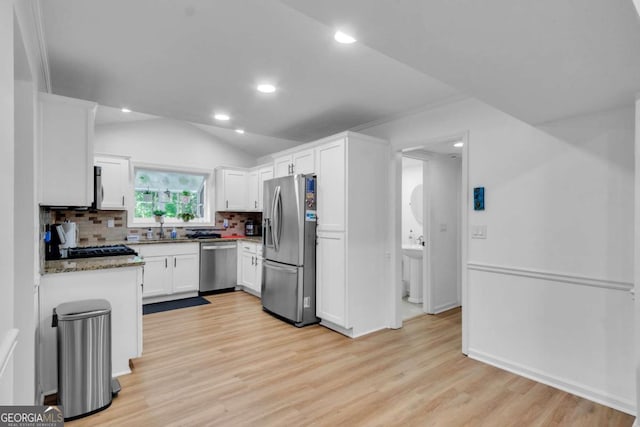 1481 Howard Way, Lawrenceville, GA 30043 - kitchen with stainless steel appliances, backsplash, white cabinetry, light wood-style flooring, and vaulted ceiling