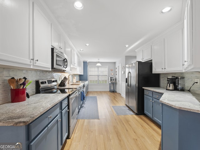 1804 Maxey Ln, Winder, GA 30680 - kitchen with stainless steel appliances, white cabinetry, blue cabinets, light wood finished floors, and recessed lighting