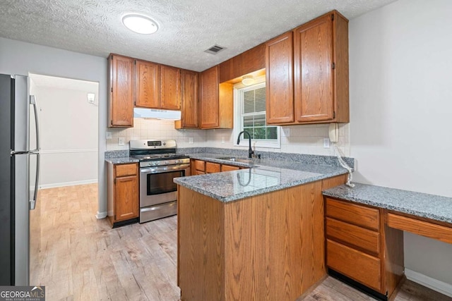 3997 Paloverde Dr NW, Kennesaw, GA 30144 - kitchen with stainless steel appliances, under cabinet range hood, brown cabinets, a peninsula, and light wood-style floors