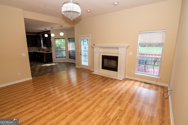 214 Hunters Chase, Byron, GA 31008 - unfurnished living room with light wood-style floors, a chandelier, and a fireplace with flush hearth