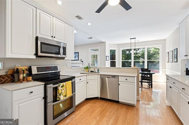 3072 Oaktree, Duluth, GA 30096 - kitchen featuring appliances with stainless steel finishes, a peninsula, light wood-style flooring, light countertops, and white cabinets