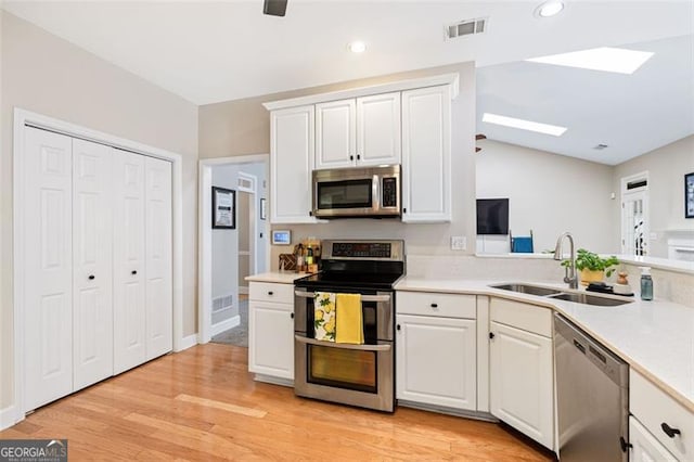3072 Oaktree, Duluth, GA 30096 - kitchen with appliances with stainless steel finishes, a skylight, white cabinets, light wood-style floors, and light countertops