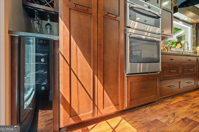 112 Springhill Ln, Clarkesville, GA 30523 - kitchen featuring stainless steel double oven, wood finished floors, brown cabinetry, and glass insert cabinets