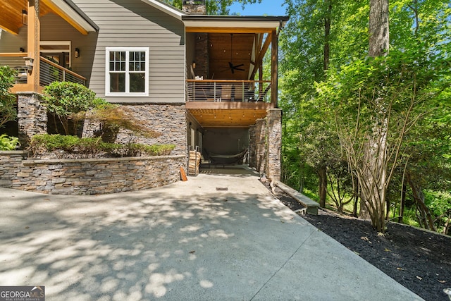 112 Springhill Ln, Clarkesville, GA 30523 - view of side of home featuring a balcony, stone siding, a patio, a chimney, and concrete driveway