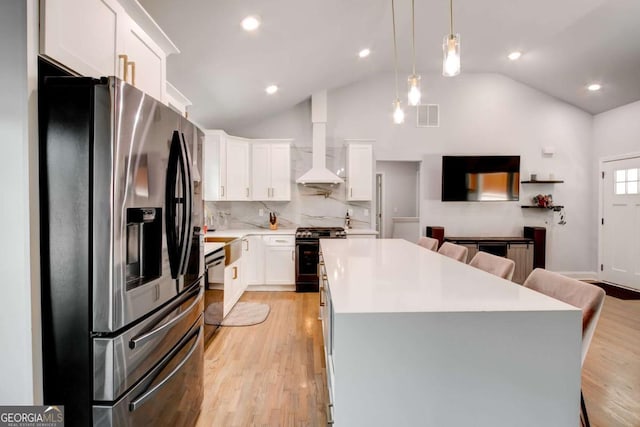 2200 Glendale Dr, Atlanta, GA 30032 - kitchen with stainless steel appliances, wall chimney range hood, vaulted ceiling, a breakfast bar, and a center island