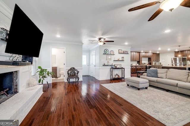 281 Noel C Conaway Rd, Guyton, GA 31312 - living area featuring ceiling fan, ornamental molding, dark wood-style floors, a fireplace with raised hearth, and recessed lighting