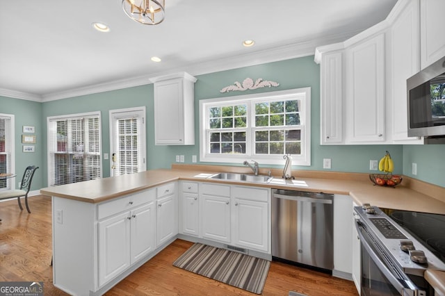 103 W Second St, Greensboro, GA 30642 - kitchen featuring appliances with stainless steel finishes, a peninsula, white cabinets, light countertops, and crown molding
