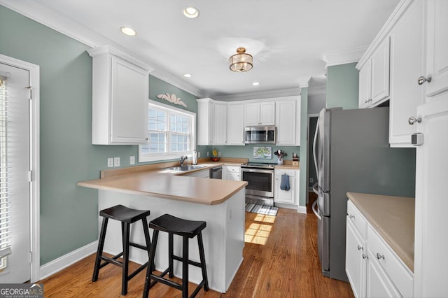 103 W Second St, Greensboro, GA 30642 - kitchen featuring appliances with stainless steel finishes, a peninsula, white cabinetry, a breakfast bar area, and recessed lighting