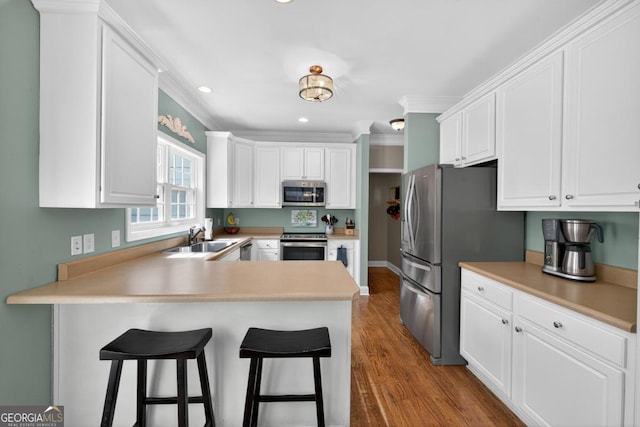 103 W Second St, Greensboro, GA 30642 - kitchen featuring stainless steel appliances, white cabinets, a peninsula, dark wood-style floors, and recessed lighting
