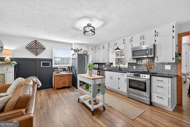 1724 Cedar Grove Church Rd, Winder, GA 30680 - kitchen with stainless steel appliances, dark countertops, decorative backsplash, wood finished floors, and a textured ceiling